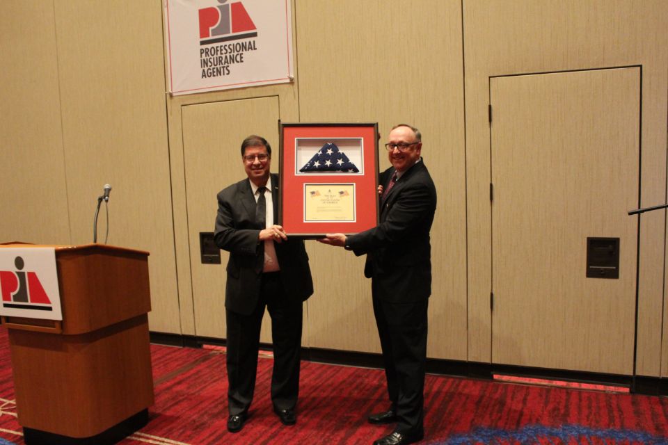 Newly elected President Bruce Blum, CPIA, and outgoing President Lloyd “Rip” Bush, CPIA, with a flag that was flown over the U.S. Capitol.